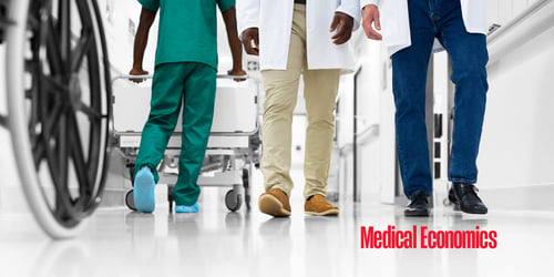 Three differently dressed individuals walk the hall of a hospital