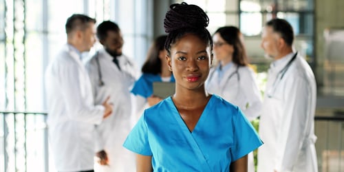 young adult nurse looking serious with team of clinicians talking in the background