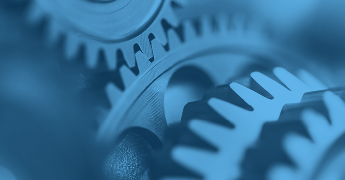 Close-up of interlocking metal cogwheels with detailed teeth in a blue monochromatic tone, showcasing mechanical precision with selective focus.