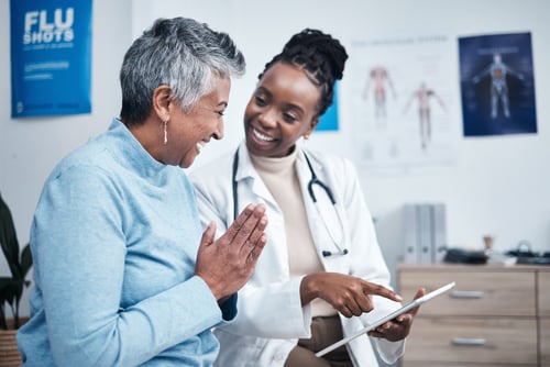  Black female doctor discusses healthcare treatment with a senior female patient.