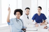 A doctor raising her hand to ask about new EHR options. 
