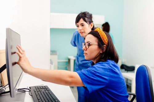 Two nurses using a computer in a hospital discussing EHR usability 