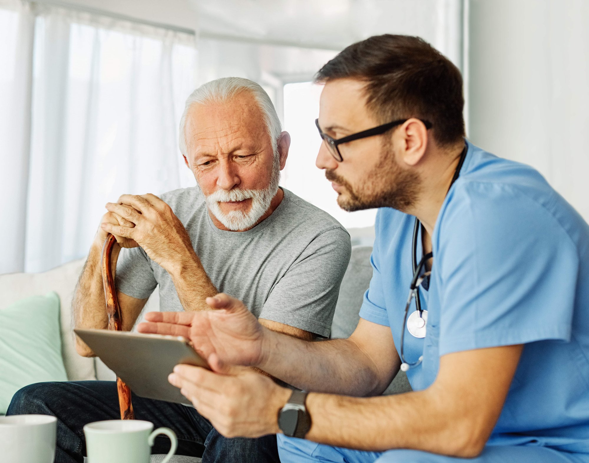 Male nurse using EHR software on a tablet to share data with their patient and improve patient care